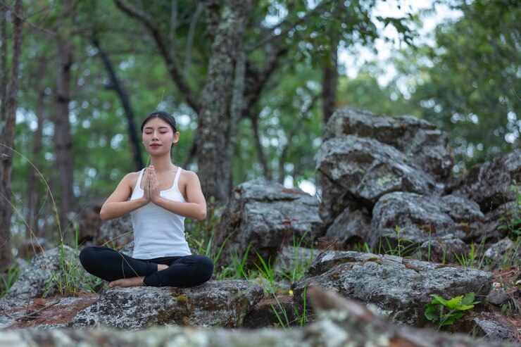 An Asian lady meditating in a park