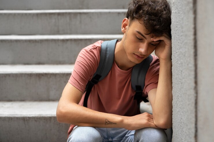 Sad teenage boy sitting on stairs