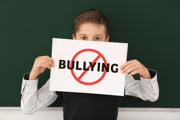 little-boy-holding-sign with crossed word bullying classroom