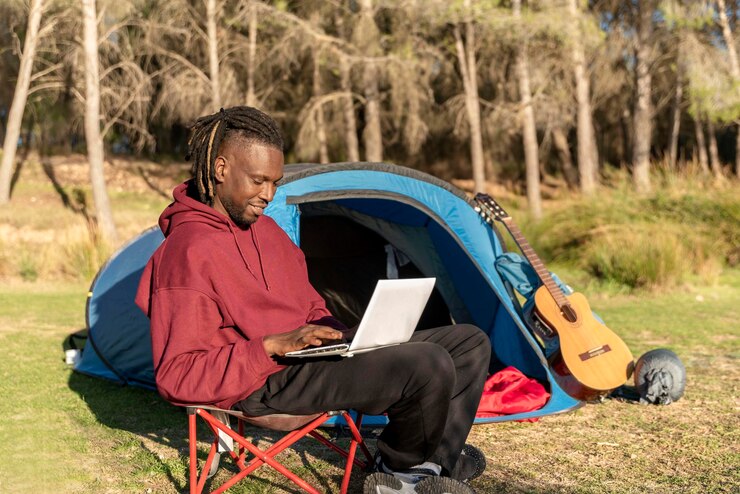 Man sitting on a camp chair using a laptop