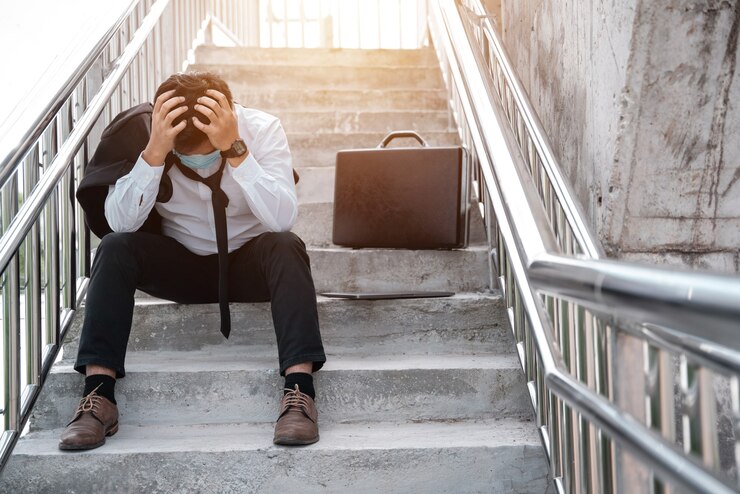 man sitting on a flight of stairs, looking stressed