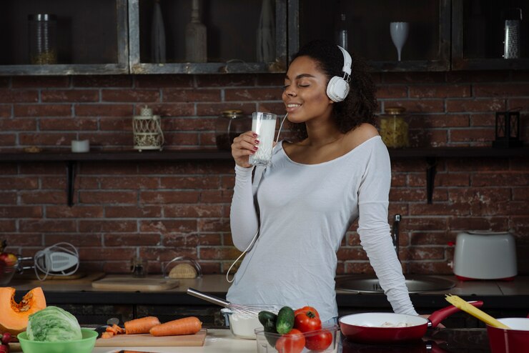 Woman listening to music as they drink a glass of milk