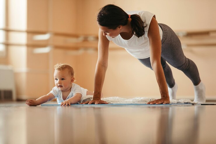 Mom doing pushups while her baby tries to imitate her