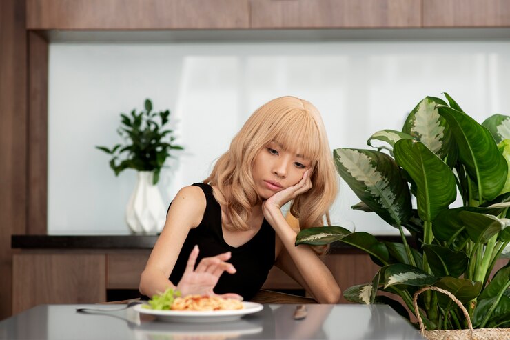 Slim-looking Asian teen pushing away a plate of food