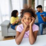 Child looks worried as her parents talk behind her