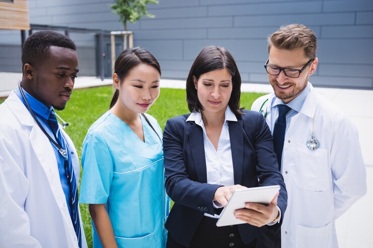 a team of doctors discussing something on a tablet