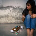 a teenager sitting with drugs on the floor