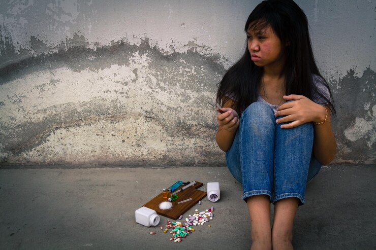 a teenager sitting with drugs on the floor